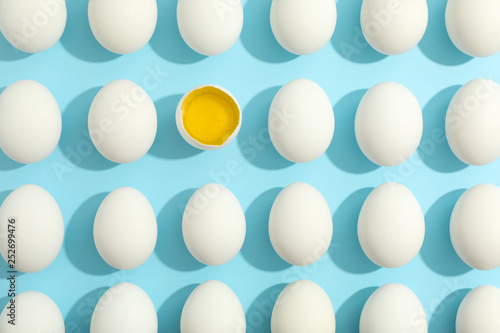 Flat lay composition with chicken eggs and half with yolk on color background  space for text