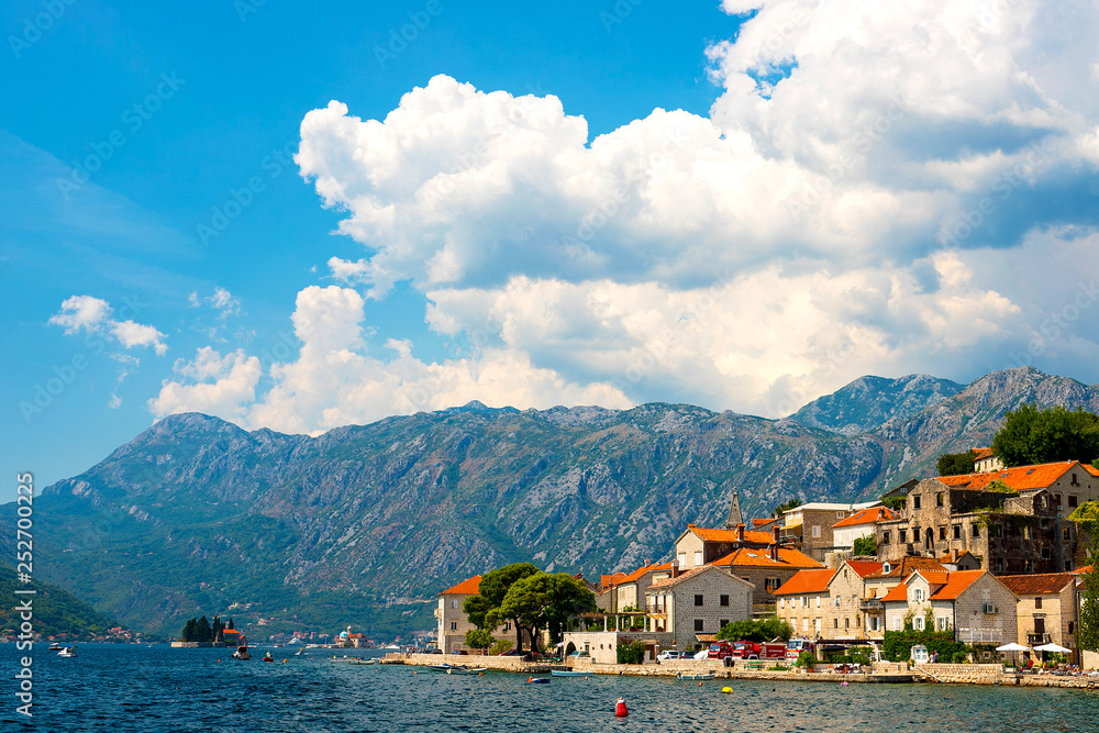 Scenic panoramic view of the historical city of Perast, located in the Bay of Kotor on a sunny day with blue sky and white clouds in summer, Montenegro, southern Europe