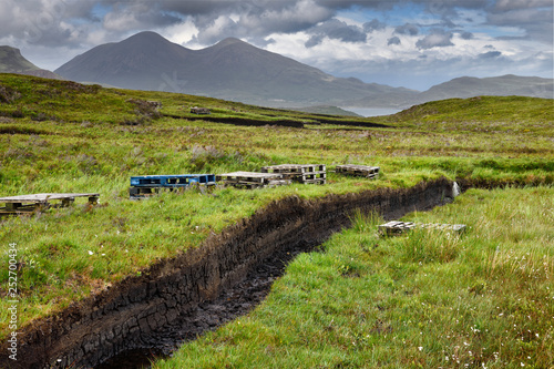Trenches cut into deep Peat of wetland moors near Drinan on Isle of Skye Scotland with Loch Slap and Beinn Dearg Mhor and Beinn Na Caillich peaks photo
