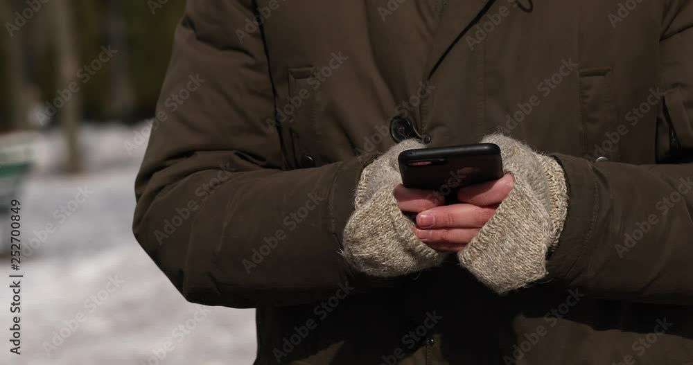 close up view of man hands using smartphone in winter. close up view of man hands using smartphone in winter.