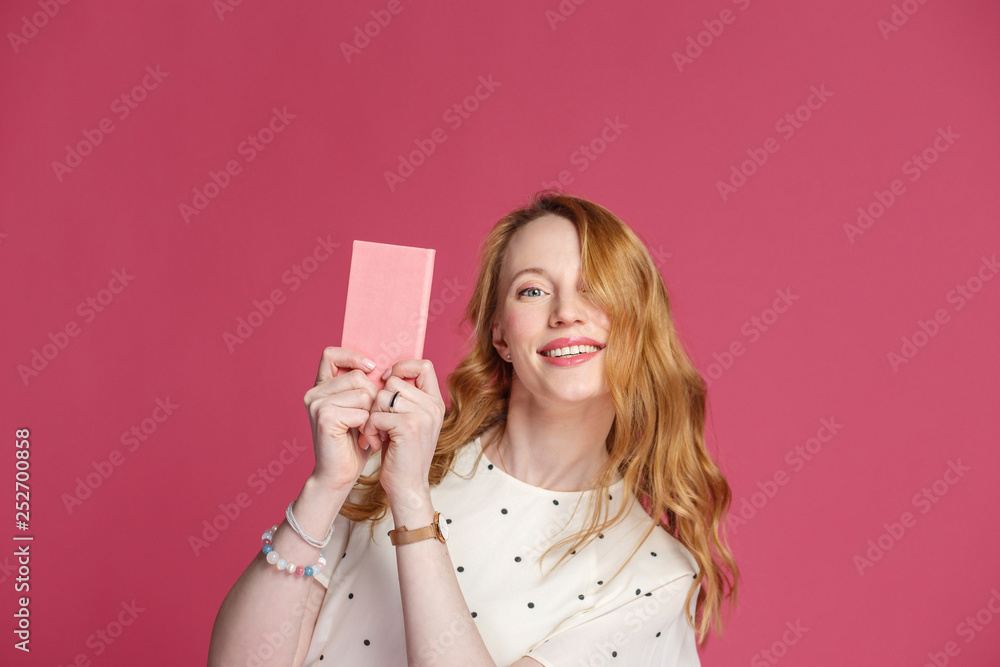 Beautiful blonde woman with pink notebook on a pink background. Female blogger. Beautiful blonde woman with pink notebook on a pink background. Female blogger.