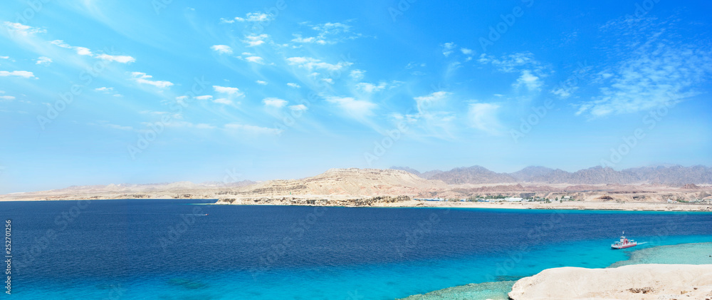 seascape large wide panorama with desert mountains, bay with ships, sunny blue sky