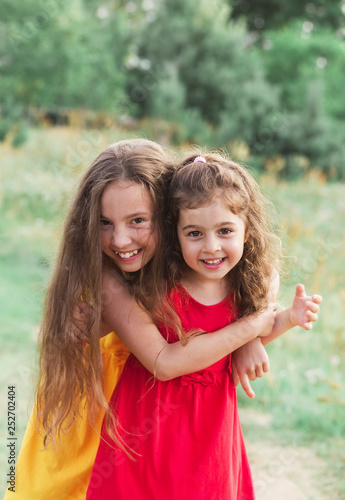 Portrait of Two Cute little girls embracing and laughing at the countryside. Happy kids outdoors