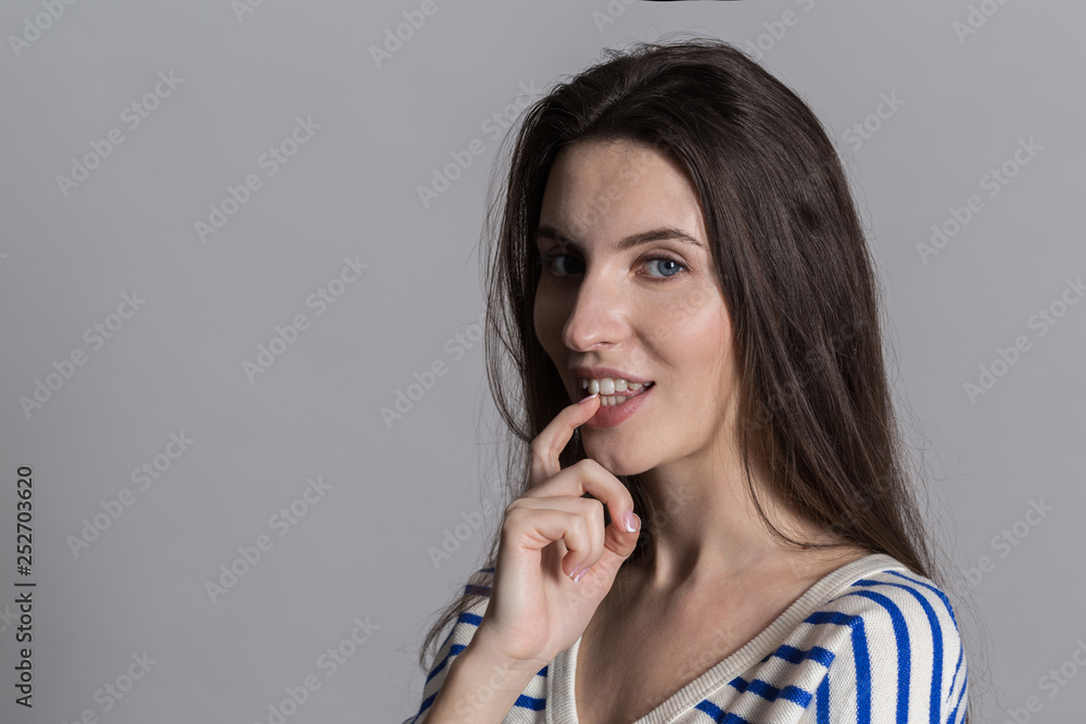 Pretty woman with fluffy hair, dressed casually against a gray studio wall Pretty woman with fluffy hair, dressed casually against a gray studio wall