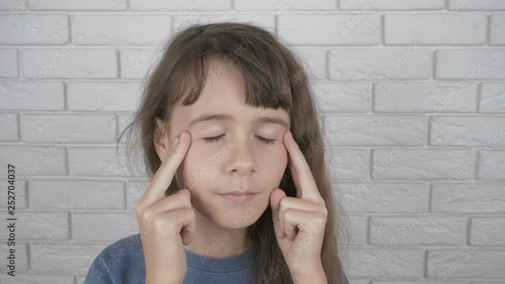 Acupressure face massage. A little girl massages points on her temples. Acupressure face massage. A little girl massages points on her temples.