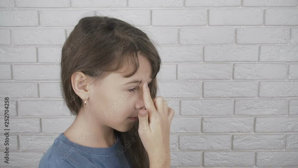 The girl makes acupressure face. The child massages a point on the forehead. The girl makes acupressure face. The child massages a point on the forehead.