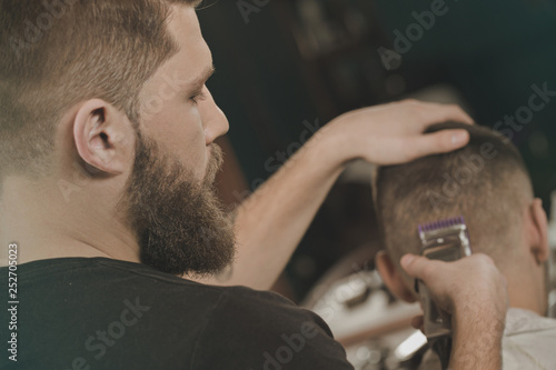 In hands of a professional. Young professional barber cutting hair