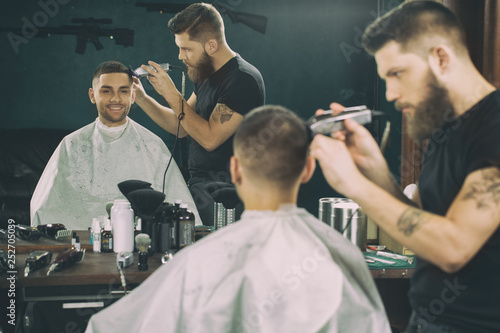 You gonna love your new hairstyle. Half length portrait of a barber working in the barbershop giving a haircut to a male client