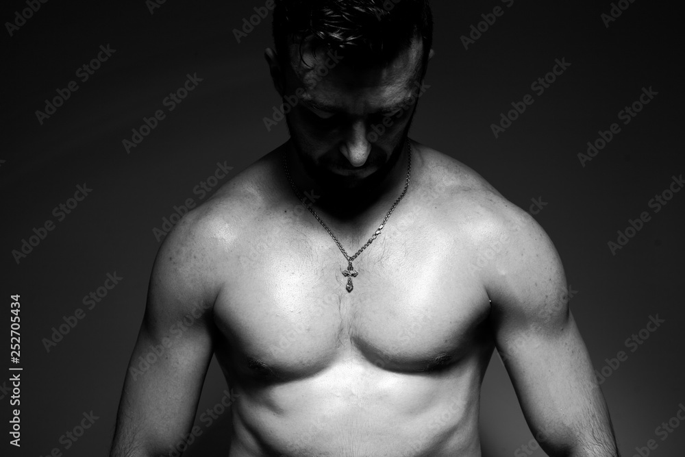 Black and white photo of a handsome and sporty guy close-up in studio