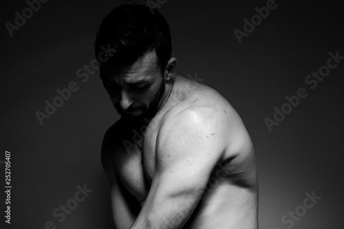 Black and white photo of a handsome and sporty guy close-up in studio