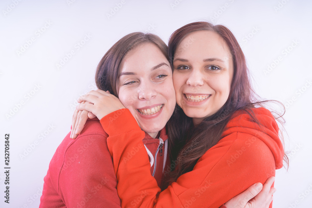 two friends or lesbians on a white background, smiling and laughing in the company of each other. The concept of female friendship and love two friends or lesbians on a white background, smiling and laughing in the company of each other. The concept of female friendship and love