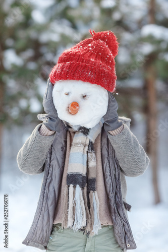 The boy is building a snowman. Boys building a snow man playing outside on a sunny snowy winter day. Outdoor family holiday on the Christmas holidays. Boy and girl playing snowballs.