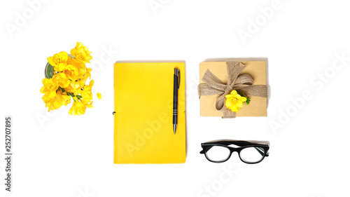 Women's home office desk. Workspace with yellow notebook, fashion glasses carton box fot gift, flower on white background. Top view. Flat lay. Valentine's Day 8 March birthday layout, online shopping.