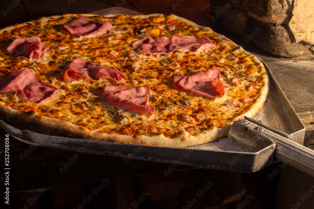 Baked pizza on the shovel in a stone oven.