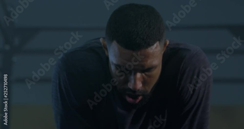 CU Portrait of handsome African American black male athlete catching breath during workout in functional gym. 4K UHD photo