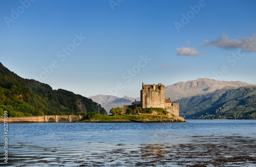 Restored Eilean Donan Castle on Eilean Donan Island with stone arch footbridge at sundown with Glenelg mountains Scottish Highlands Scotland