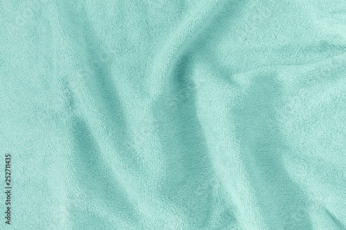 The texture of a crumpled terry towel. Empty light turquoise background.