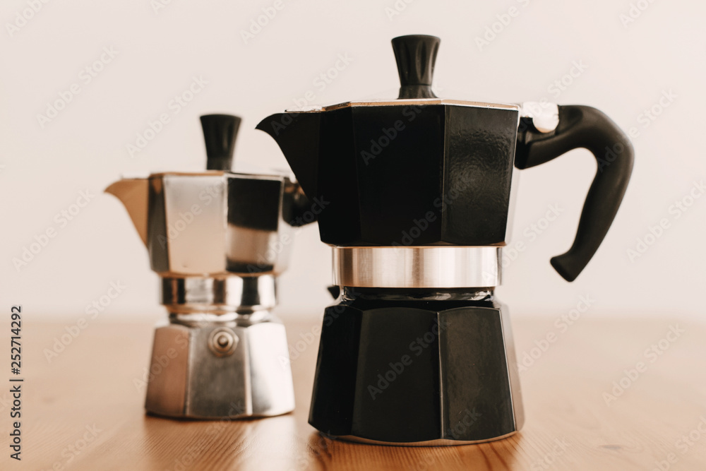 Steel and black geyser coffee makers on wooden table. Alternative coffee brewing method. Stylish accessories and items for alternative coffee Steel and black geyser coffee makers on wooden table. Alternative coffee brewing method. Stylish accessories and items for alternative coffee