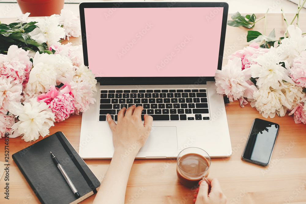 Hands working on stylish laptop with empty screen, coffee cup,  notebook,phone, pink and white peonies on wooden table with space for text.  Freelance concept. International womens day. Freelancer. Stock-Foto | Adobe  Stock