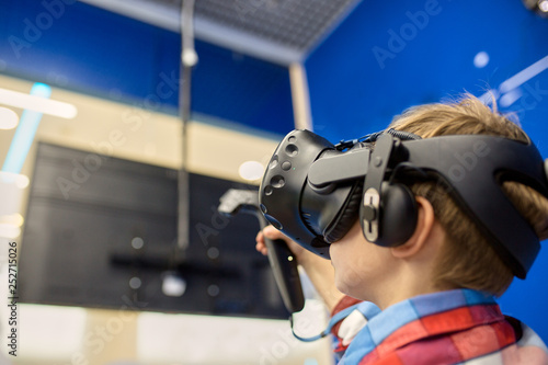 modern technology, gaming and people concept - boy in virtual reality headset or 3d glasses playing videogame at game centre