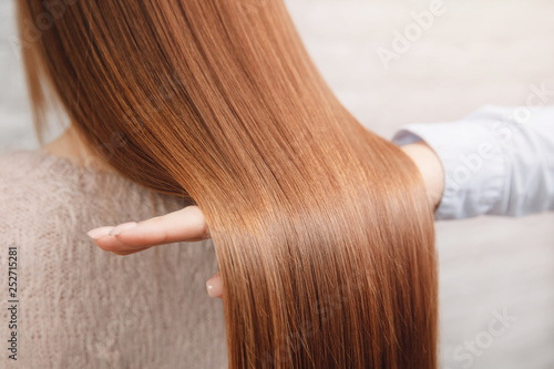 Master barber shows healthy texture of client hair after restoration, nutrition and dyeing procedure photo