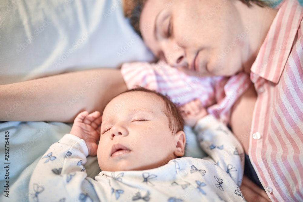 Portrait of newborn baby and mother sleeping on bed, resting together Portrait of newborn baby and mother sleeping on bed, resting together