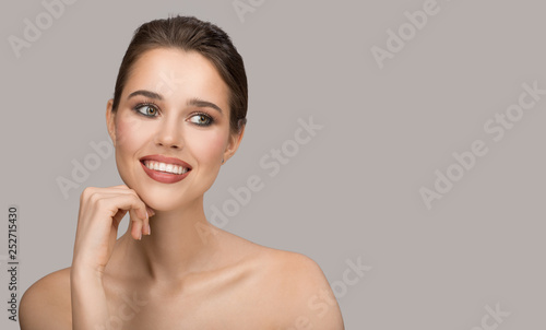 Portrait of young woman. Perfect clean skin and beautiful smile. Gray background.