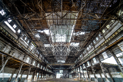 Light industrial interior of an old building with damaged ceiling and walls. Abandoned architecture of big broken warehouse inside  ruins and demolition concept.