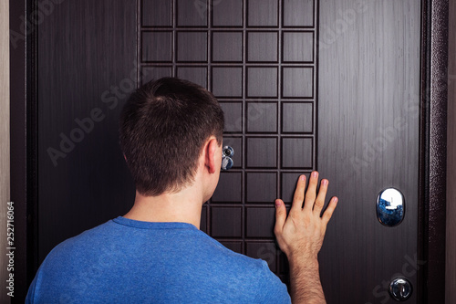 Caucasian man looks through the peephole.