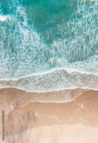 Imagem aérea de praia com ondas, mar azul e areia rosa, na costa leste da Australia