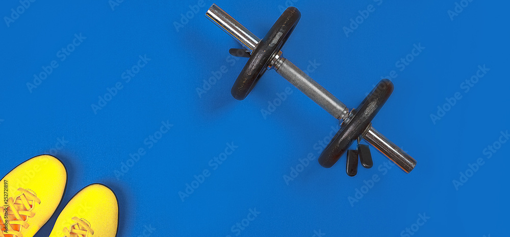 Fitness equipment and space for text on bright blue background. Sport lifestyle concept with metal dumbbell and yellow sneakers. top view, flat lay Fitness equipment and space for text on bright blue background. Sport lifestyle concept with metal dumbbell and yellow sneakers. top view, flat lay
