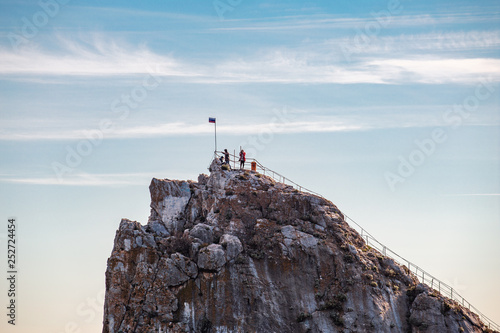 People on top of mountain or rock cliff, summer tourism and travel destinations