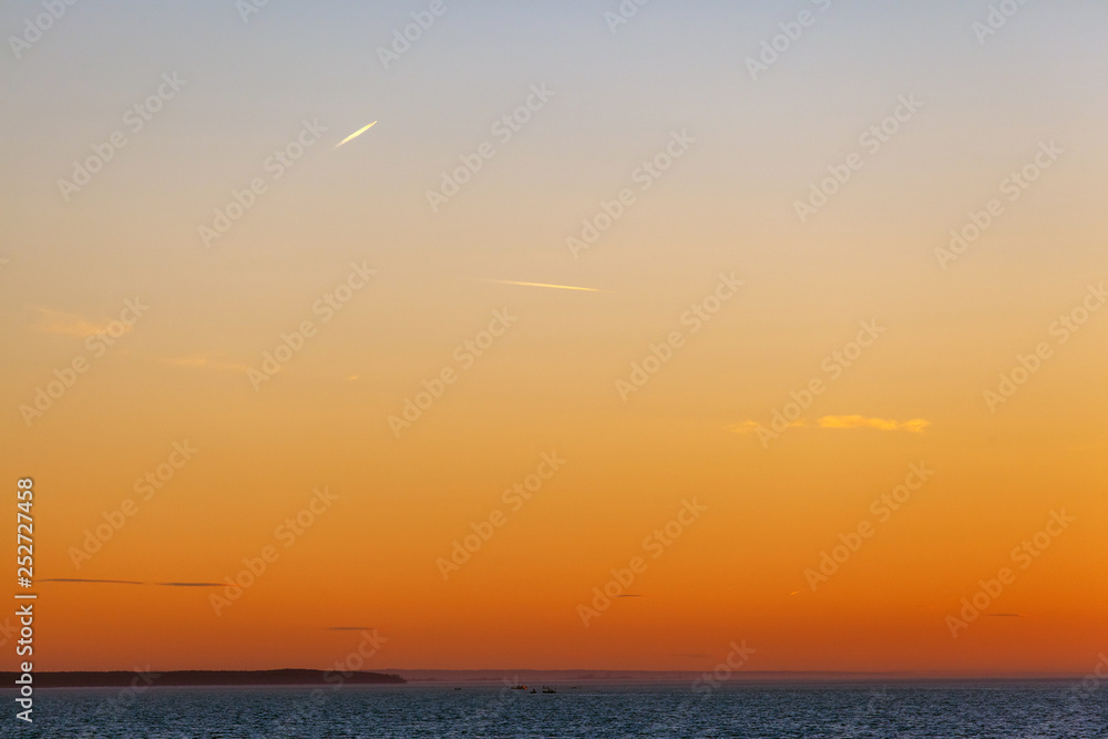orange sky over the sea during sunset with a coastline on the horizon