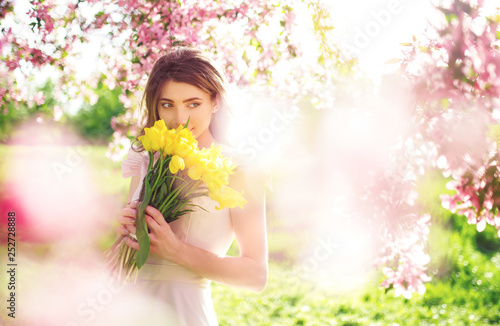 Beauty Portrait of Beautiful Young Brunette Woman In Nice Spring Dress With A Bouquet Of Tulips.Spring Style. Beautiful Spring Garden. Fashion Spring Summer Photo. Fashion and style concept. Long edge