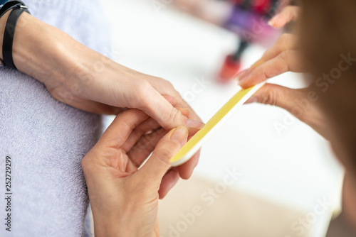 Closeup view of professional manicurist filing fingernail