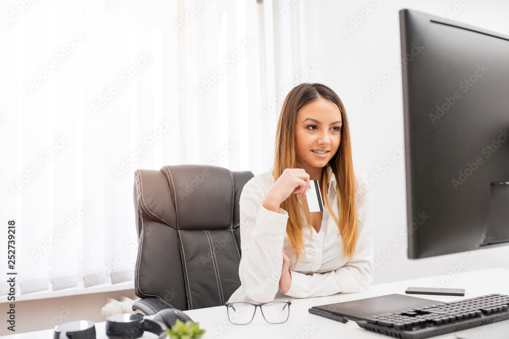 Cute young woman using her credit card online. Cute young woman using her credit card online.