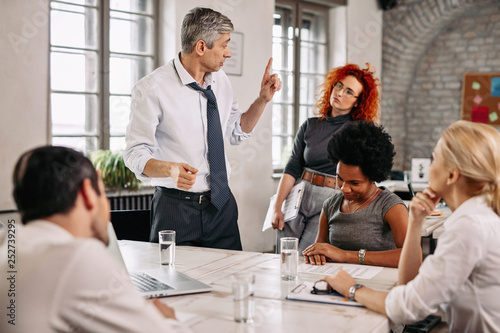 Mid adult manager having a business meeting with colleagues in the office.