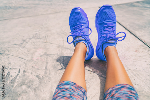 Running shoes fashion activewear healthy active people lifestyle. Selfie woman taking pictures of royal blue trainers during workout at gym floor outside.