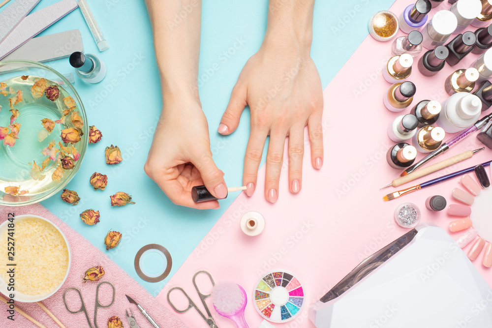 Concept of nail art. Woman gives herself a manicure on a white table Concept of nail art. Woman gives herself a manicure on a white table