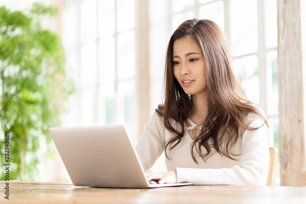 attractive asian woman using laptop in living room attractive asian woman using laptop in living room