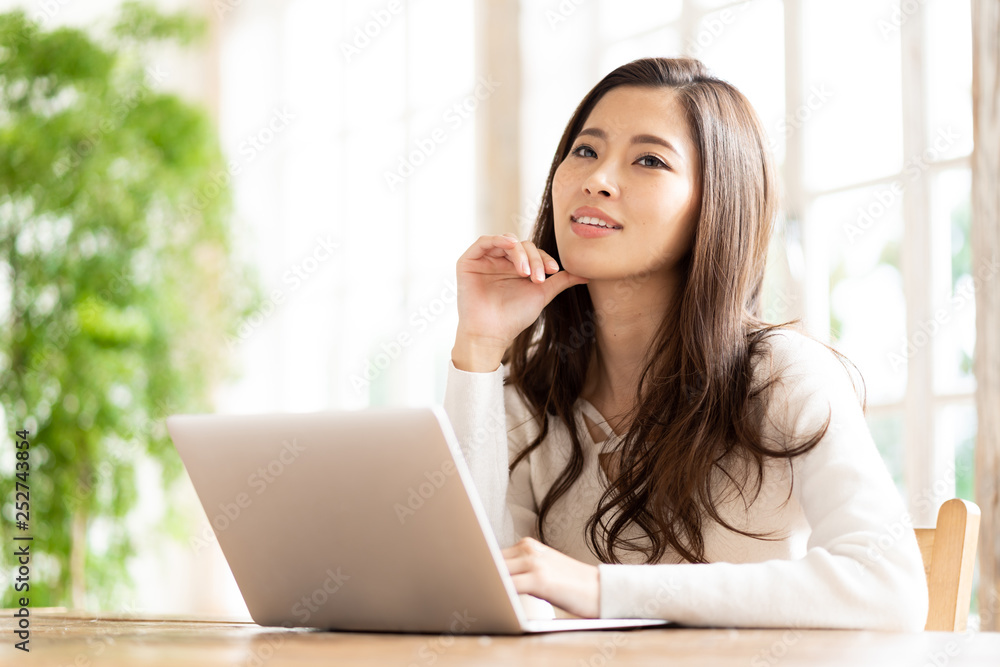 attractive asian woman using laptop in living room attractive asian woman using laptop in living room