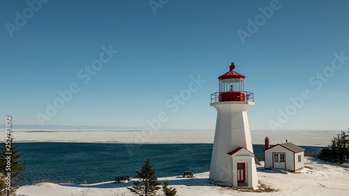 Cap Gaspe lighthouse in Forillon National Park on a bright sunny day with the Gulf of St-Lawrence in the background. photo