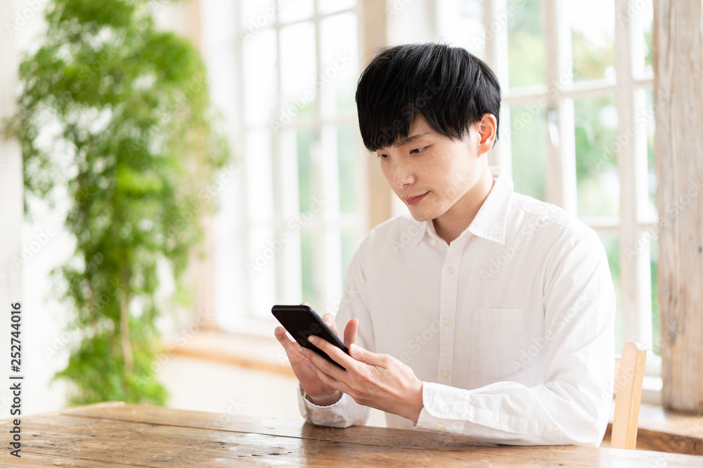 young asian man using smart phone in living room young asian man using smart phone in living room