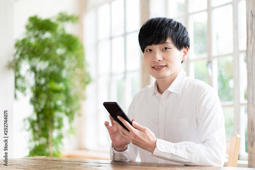 young asian man using smart phone in living room