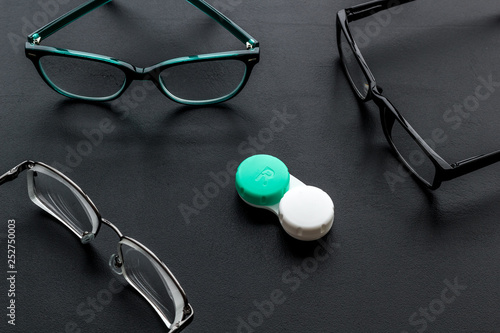 Eye problems. Glasses with transparent lenses and contact lenses on black background