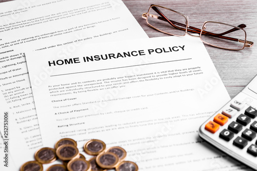 Home insurance policy. Coins, calculator and home insurance policy. Business background concept. Mortgage loading real estate property with house and money concept