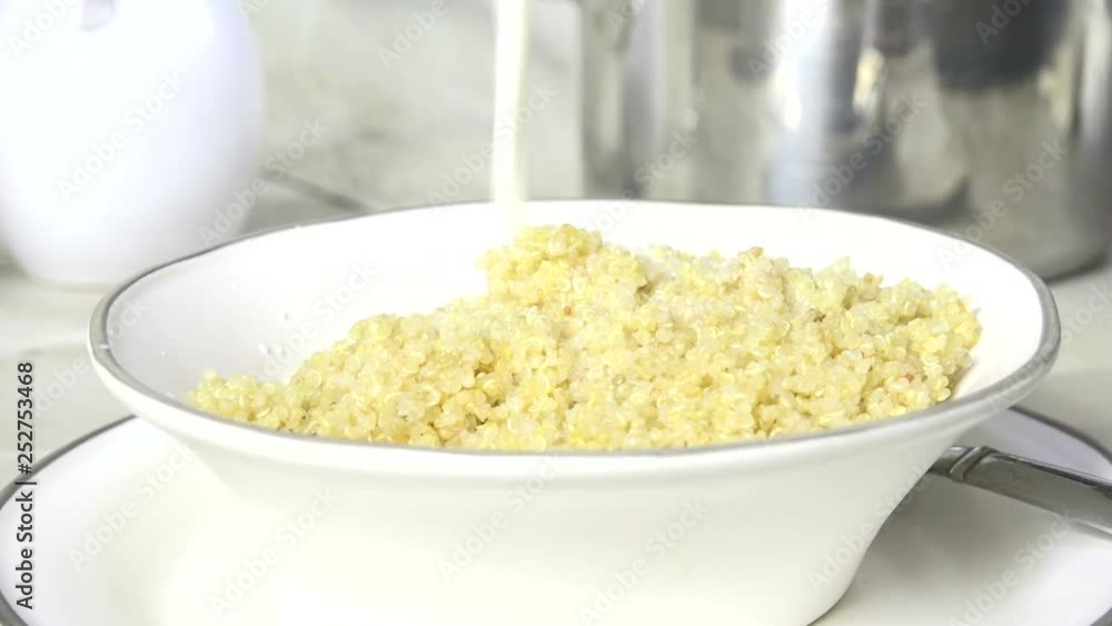 Pouring milk on a bowl of hot quinoa breakfast cereal, slow motion