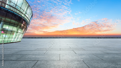 Empty square floor and modern city skyline with buildings at sunset