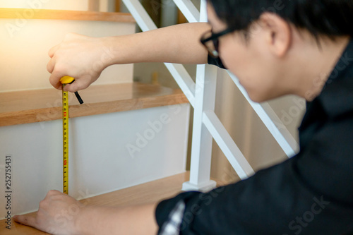 Canvastavla Young Asian worker using tape measure for measuring riser and thread on stair in the house