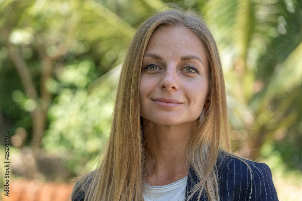 Beautiful caucasian blonde girl in a business suit in nature background. A portrait of a young business woman in tropical garden, Thailand Beautiful caucasian blonde girl in a business suit in nature background. A portrait of a young business woman in tropical garden, Thailand